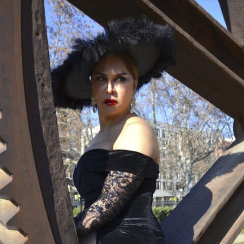 Eine Frau trägt ein schwarzes Kleid und einen schwarzen Hut.