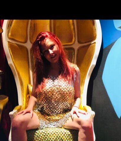 Eine Frau in einem Kleid sitzt auf einem goldenen Stuhl.