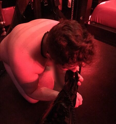 Ein Mann kniet auf dem Boden und hält einen schwarzen Stiefel.